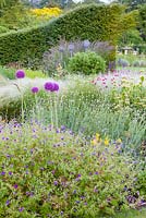 The herbaceous border in the foreground features plants including: Geraniums, Alliums, Phlomis russeliana, Lychnis coronaria, Agastache and Stipa. Bluebell Cottage Gardens, Cheshire.