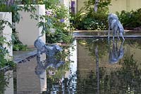 Two wire dog sculptures drinking from the pond in Dogs Trust: A Dog's Life garden at RHS Hampton Court Palace Flower Show 2016