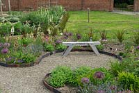 Rustic wooden seat in the newly planted garden with gravel path.