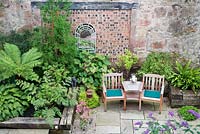 Ferns, hostas, buddleja by seating area and mirror 'window'