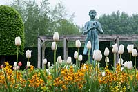 Tulipa 'Maureen' and Erysimum Cheiri 'Fire King' surrounding the statue, 'The Lamp of Wisdom' by Natham David in the formal garden at Waterperry.