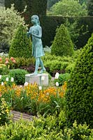 The Lamp of Wisdom statue in a formal garden amongst topiary box cones surrounded by Tulip 'Maureen' and Erysimum cheiri 'Fire King'.