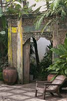 Old traditional carved doorway and wooden chair on patio in tropical garden - Java, Indonesia