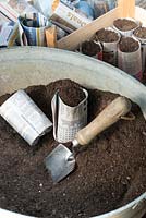 Potting bench with newspaper pots, compost and trowel.