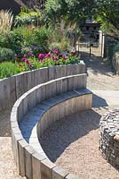 Wooden seating and gravel path with late summer mixed border behind, Jo Thompson garden Design,  Ticehurst, East Sussex 