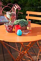 Decorative bright orange garden furniture with colourful ornaments and succulents in pots. Patio garden. Owner: Pattie Barron