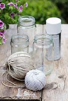 Making garden lanterns. Ingredients required: jam jars, string, white spray paint