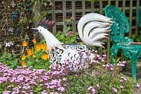 A garden in summer with a metal chicken ornament.