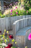 Wooden raised flower bed with seating and gravel path with late summer mixed border behind. Jo Thompson garden Design, Ticehurst, East Sussex