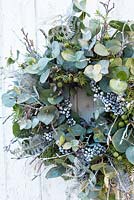 White and silver Christmas wreath with euclayptus juniper berries and sprayed white fern leaves, ivy berries and twigs