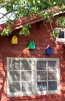 Orange painted summerhouse with yellow, green and blue birdhouses.