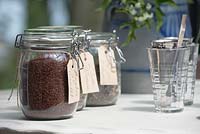 Labeled glass jars filled with different teas and teaglasses on a table.