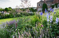 Herbaceous borders in front of the house include scabious, thalictrum, delphiniums, salvias and achilleas. Felley Priory, Underwood, Notts, UK