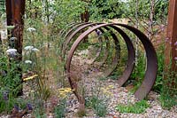 Brownfield - Metamorposis. Repeating rusted steel hoops buried incrushed stone rubble, Design: Martyn Wilson. Sponsors: St. Modwen. RHS Hampton Court Palace Flower Show 2017