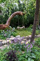 The Zoflora and Caudwell Children's Wild Garden. Garden swings on fallen tree trunk. Designers: Adam White and Andree Davies. Sponsors: Zoflora. RHS Hampton Court Palace Flower Show 2017