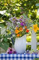 Jug of edible flowers and herbs. Borage, lavender, fennel, mint, marigold, nasturtium, monarda, origanum, echinacea purpurea, chives allium cepa and chamomile