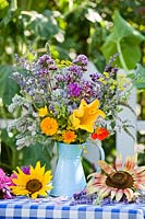 Jug of edible flowers and herbs. Borage, lavender, fennel, mint, marigold, nasturtium, monarda, origanum, echinacea purpurea, chives, allium cepa, chamomile and squash