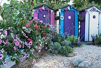Fun by the sea, with an old rowing boat in front of a line of beach huts is planted with, blue, white and purple petunias, ivy leaved geraniums and zonal geraniums. Designed by: Tony Wagstaff, Sponsored by Sovereign Play Equipment.