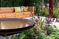 A small garden with circular steel bird bath and a long wooden bench is an ideal place to meet.  Plants include: Agastache 'Kudo Gold', Alchemilla mollis, Penstemon, Pennisetum thunbergii 'Red Buttons' and Hart's Tongue Ferns. Designed by: The Association of Professional Landscapers