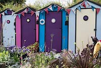 Summer planting in front of a row of beach huts.  Plants included: Petunias, Agapanthus, Eryngium giganteum, Lychnis coronaria and Verbena bonariensis.  Designed by: Tony Wagstaff