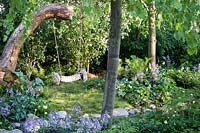 Hampton Court Flower Show, 2017. The 'Zoflora and Caudwell' Children's Wild Garden. Children's rope swing in shady woodland garden