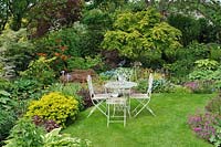 Chairs and table surrounded by mixed borders - Jardin de Maggy, Centre-Val de Loire, France