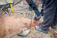 Builder using angle grinder to cut bricks for make steps in a small London Garden