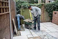 Emptying cement from wheelbarrow onto prepared ground for laying stone paving on terrace