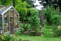 Garden view with wooden greenhouse and vegetable beds