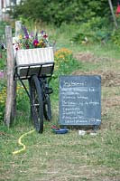 Bicycle basket filled with flowers and slate board with the list of which vegetables to harvest