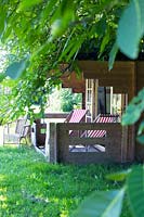 Summerhouse with two deckchairs on the veranda in the orchard.