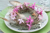 Small Easter wreath of hay with flowers of hyacinthus and feathers