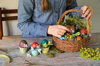 Placing decorated dyed easter eggs into basket