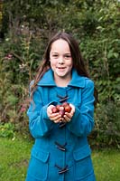 Young girl holding conkers