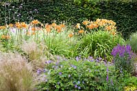 The Wiggly beds. Hemerocallis fulva, Geranium 'Rozanne', Stipa tenuissima, Verbena bonariensis, Veronica spicata 'Royal Candles'. Hill House, Glascoed, Monmouthshire, Wales. 