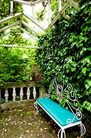 Ornate metal bench with blue cushion. Villa Singer Garden. Milan. Italy
