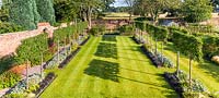 An elevated view of the garden designed by Louise Harrison-Holland. The walled garden has long, linear borders, with plants including pleached Pyrus calleryana 'Chanticleer', Japanese anemones, Stachys, Persicaria, Ophiopogon planiscapus 'Nigrescens' and Miscanthus sinensis 'Kleine Fontaine. 