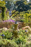 An armillary sphere provides a focal point in a modern Cheshire country garden, designed by Louise Harrison-Holland. Planting includes roses and Stipa tenuissima.