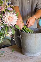 Man cutting stems of bouquet into bucket
