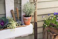 White pallet planter with garden tools and a mix of flowers, grasses and herbs