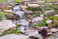 Waterfall. Naturalistic Water Garden - Jackie Knight's Just Add Water - RHS Chatsworth Flower Show 2017. Designer: Jackie Sutton - Built and sponsored by Jackie Knight Landscapes