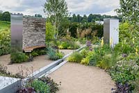 Dry stone wall, wooden bench, water feature rill channel and beds of herbaceous perennials, grasses, shrubs and trees - Cruse Bereavement Care: 'A Time for Everything' - RHS Chatsworth Flower Show 2017 - Designer: Neil Sutcliffe - Sponsor: London Stone