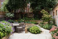 Late Summer garden with seating area and raised beds 