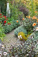 Kitchen garden in late summer with herb and vegetable borders and dahlias. Tagetes tenuifolia 'Gnom', Dahlia 'David Howard',  Dahlia 'Garden Miracle', Santolina chamaecyparissus and Dahlia 'Bishop of Dover'. Design: Alie Stoffers