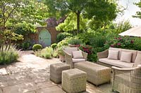 Wicker furniture on patio in summer with Rosa and mixed decorative containers