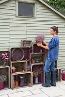 Woman potting up plants to add onto the vintage wooden crate storage