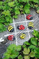 Garden craft making painted Bumble bees and Ladybirds with stones.  Draw a noughts and crosses board with chalk and use the painted insects as game pieces