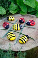 Garden craft making painted Bumble bees and Ladybirds with stones. Long grasses laid out to make a noughts and crosses board