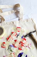 Printing onto fabric bag with fresh flowers. Remove the stems from the flowerheads and lay the flowers face down on to your bag in the pattern you want and secure with pieces of masking tape then gently hammer on the flowers.