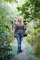 Abigail Ahern designer in her garden with view from small garden down the path to living area - Hackney garden London 